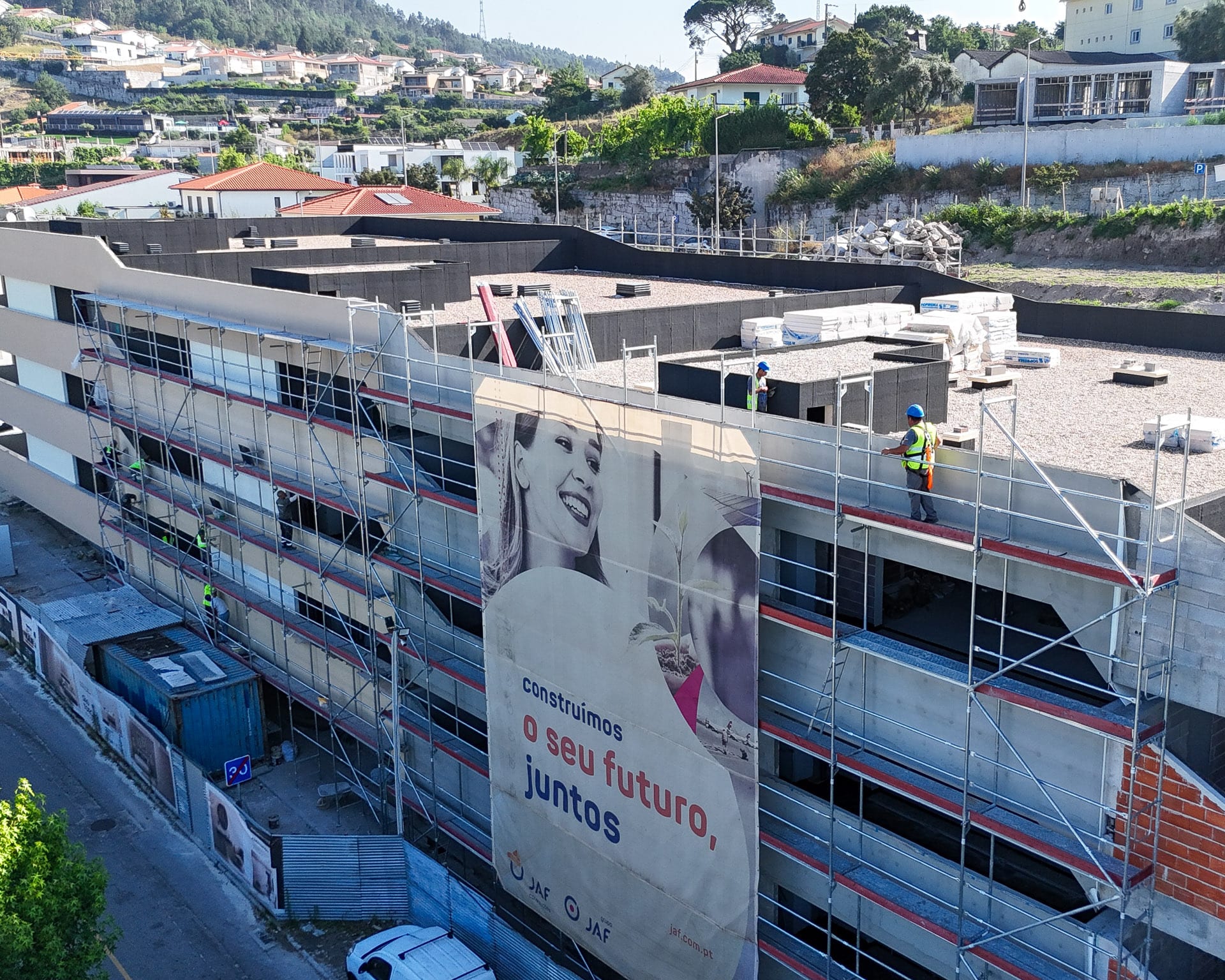 JAF Construções – aerial view of a building under construction, with scaffolding and crews on the façade