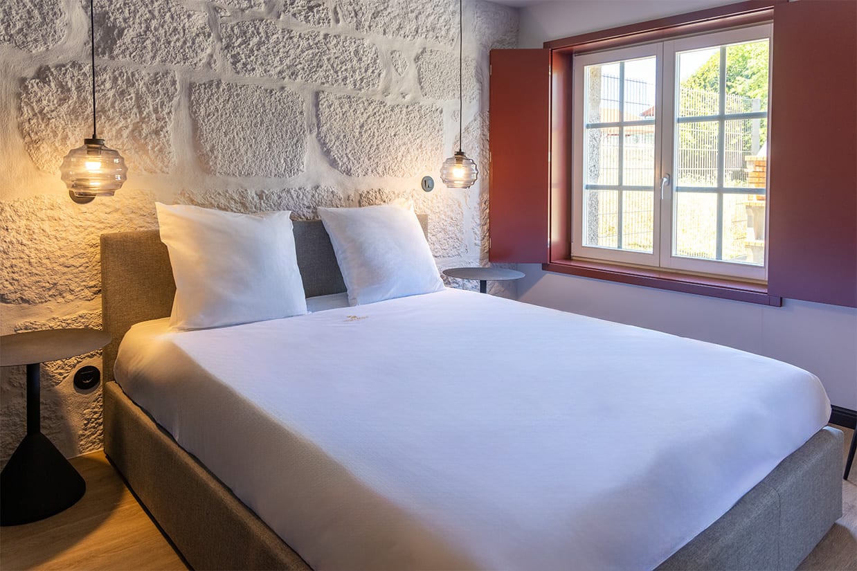 Bedroom with a stone wall, Rua da Liberdade Apartments, Guimarães