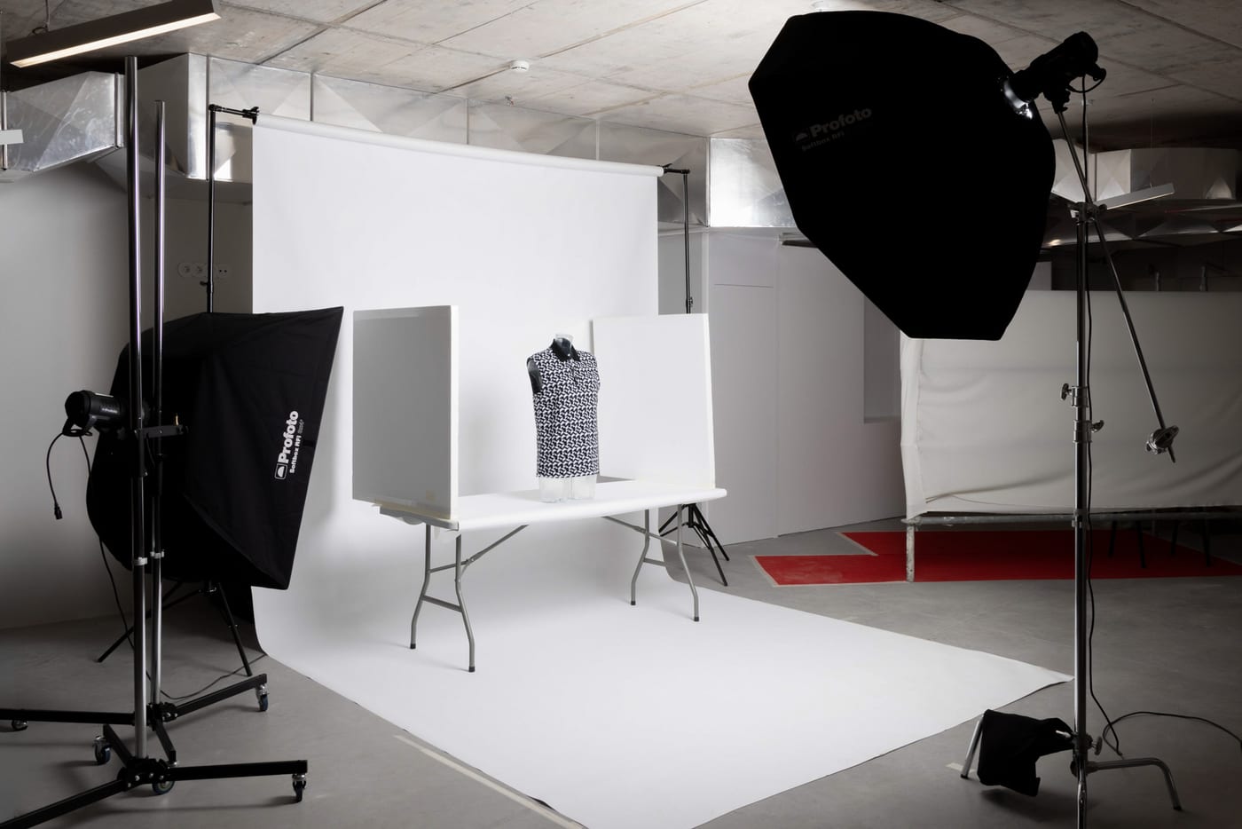 A product photography table set up on a continuous white backdrop, between two Profoto softboxes