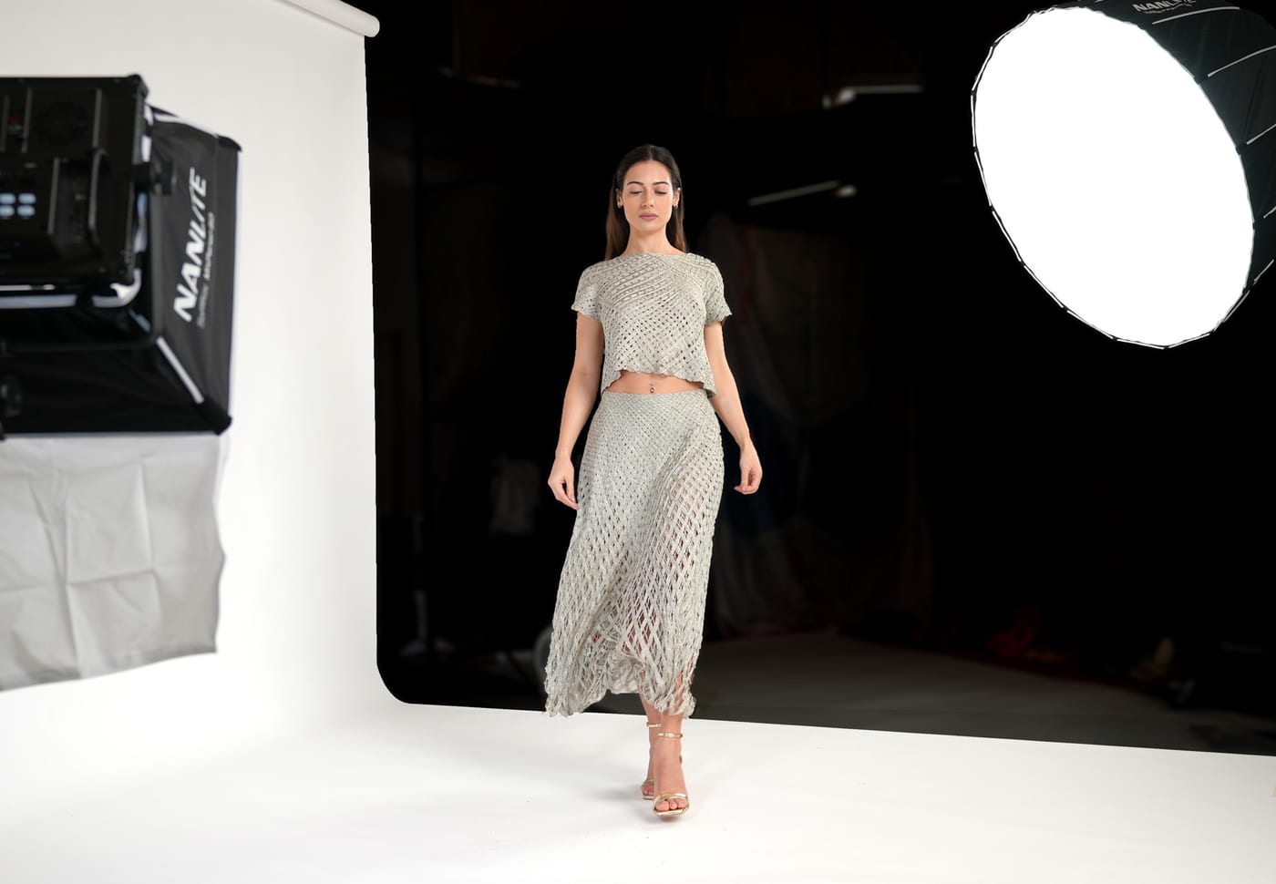 A fashion shoot under way in the studio, with a model on a continuous white backdrop and studio lighting